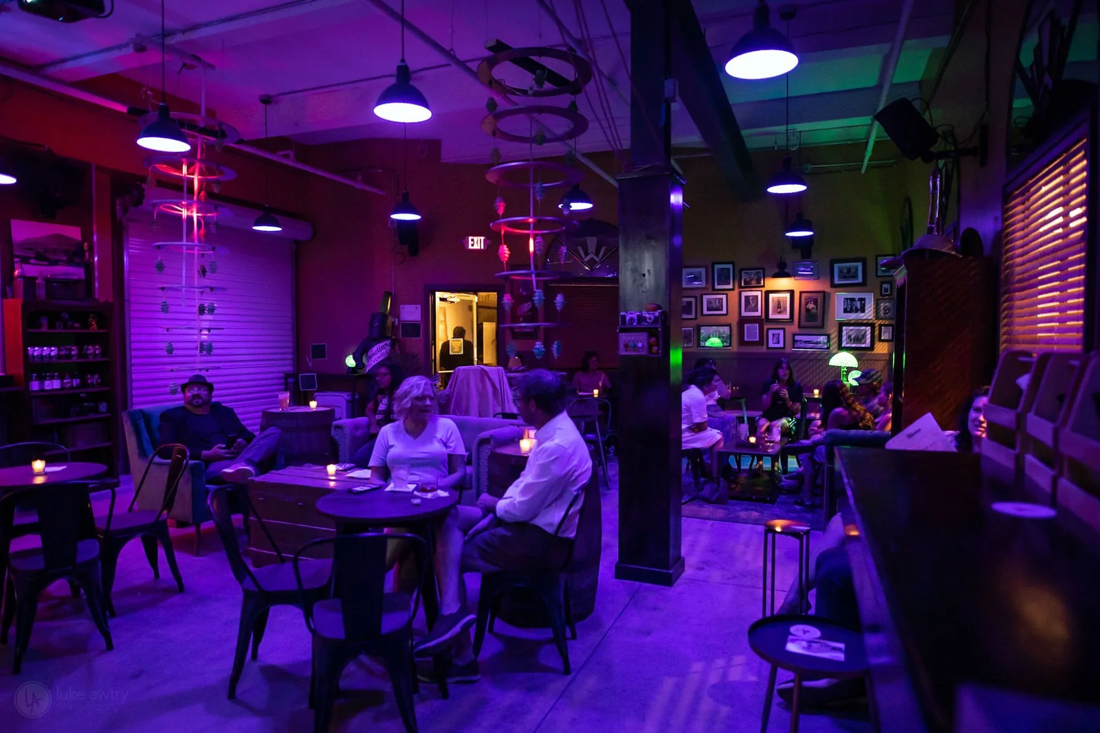 A wide view of the Venetian Soda Lounge, guests seated across the room under coloured light and hanging fixtures.
